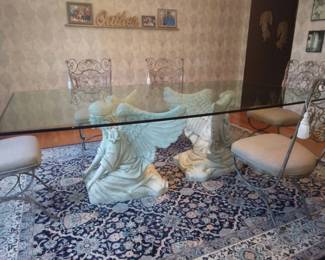 Unique FUNCTIONAL ART! This is a custom made, one-of-a-kind gorgeous Angelic Dining Table. Twin angels kneel quietly under this unique and original glass top table. Sculpted with the utmost care and attention to detail. Featuring intricate details on their wings and hair. Lavishly clothed in flowing gowns. Elegant triple waterfall edge finish on boat shaped ¾” thick glass top. Seats up to 12 people. Base 29” Tall. Wingspan 36” Glass top 4’ X 8’. Includes 12 wrought iron dining room chairs finished in a light bronze and cream colored cloth seats. Beautiful scrolls and details on chair back. A beautiful and unique dining room table to bring a little heaven to your family gatherings. Includes original architectural drawings signed by the artist. If you want a table NO ONE else in the world has, this one is for YOU!