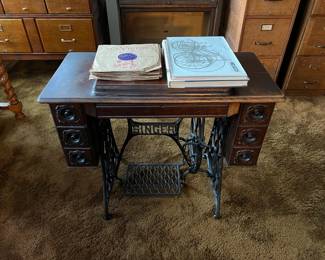 This is an unmistakable Singer sewing cabinet for a treadle sewing machine.  On top are several RCA Victor LPs.