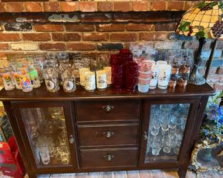 There are a few collections of glasses and stemware in this photo, as well as the Tiffany-style lamp, and let's not forget the cabinet in the center of the picture.