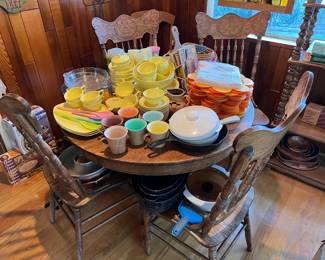 More dishes are seen here, along with the four matching chairs and the dining table.  There is a wooden shelf unit in the corner of the picture.