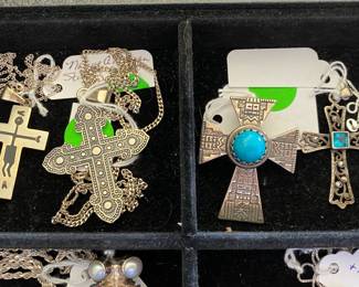 These crosses are all sterling...the lighting make them appear to be a different color tone.  