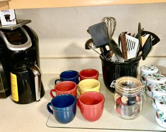 Keurig coffee pot, coffee mugs, kitchen utensils, jar of game pieces