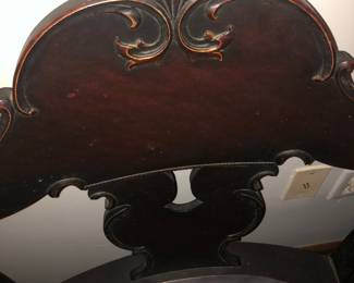 CLOSE UP VIEW OF CREST HAND CARVING OF LAWRENCE FISHER VERY HEAVY SOLID MAHOGANY CARVED MUSIC CHAIR.  SO HEAVY IT TAKES 2 HANDS TO LIFT IT.    