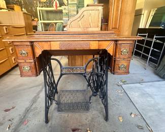 Antique Singer sewing machine (machine folds up from inside of table). Drawers on each side, wrought iron legs and pedal. 