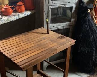 Vintage table, rug beater, and drying rack.  Storage cabinet and metal teapots.