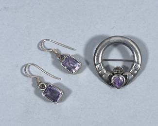 STERLING SILVER JEWELRY | Including a sterling silver Claddagh brooch with Celtic design of 2 hands holding a faceted purple stone, marked on back “925” (6.1g), and pair of square sterling silver earrings with cut purple stone, marked “925” (3.5g); Total weight: 9.6g -  dia. 1 in (brooch)