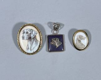 (3pc) DOG PENDANTS & BROOCHES | Including carved stone pendant with mixed metal relief, and 2 painted ceramic dog pendants/brooches. - w. 1.5 x l. 1.75 in (largest)