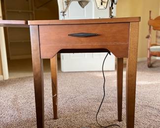 Vintage Singer sewing machine housed in a beautiful walnut cabinet. This piece combines craftsmanship with functionality, offering a charming nod to the past. Perfect for collectors or those who appreciate classic design and quality woodworking.