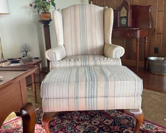Elegant Queen Anne wingback chair with matching hassock. Features high-quality cherry wood and beautifully curved legs, both in excellent condition. Craftsmanship shines through—timeless style to any room.