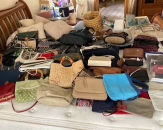 Lots of purses placed on a king size bed.