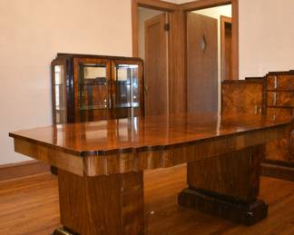 Extraordinary 1930s Art Deco dining room set by Long & Wexlear, a renowned Australian furniture manufacturer. These high-quality, handcrafted pieces captured the essence of the Art Deco movement—clean lines, geometric shapes, and streamlined elegance. The rich, figured burl wood, likely walnut or mahogany, is finished with a high-gloss lacquer—highlighting the intricate natural patterns of the wood—and the chrome hardware adds an industrial touch, further enhancing the set’s luxurious feel. Table, vitrine style display cabinet, and sideboard - there's also chairs with custom leather upholstery!