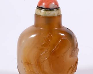 Reverse of the stunning Chinese hard stone snuff bottle of compressed bulbous form with a concave lip and recessed foot, carved to display a pair of ducks swimming amidst lotus plants, with a lone monkey perched on a stylized rock, holding a peach in its upraised paw; jade and coral stopper.
