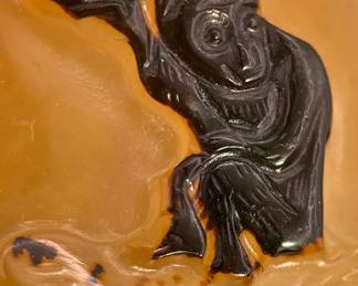 Closeup of the monkey seated on a rock and holding a peach in its upraised paw