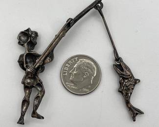 Reverse of whimsical vintage silver tone fisherman brooch, joyous young man landing a fish
