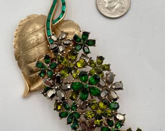 Vintage Crown Trifari brooch, heart-shaped gold tone metal leaf with stem of blossoms in a range of green faceted glass stones