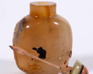 Another view of stunning Chinese hard stone snuff bottle of compressed bulbous form with a concave lip and recessed foot, carved to display a pair of ducks swimming amidst lotus plants, with a lone monkey perched on a stylized rock, holding a peach in its upraised paw; jade and coral stopper.