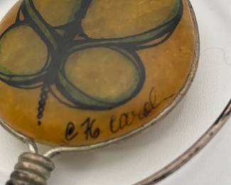 Closeup of art glass and metal wire pendant, signed 76 Carol