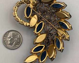 Reverse view of vintage leaf shape brooch, gold tone metal hand set with green rhinestones in floral frames, and larger rich blue and Aurora Borealis navette rhinestones 