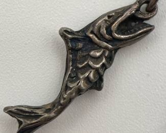 Closeup of whimsical vintage silver tone fisherman brooch, the fish on the hook