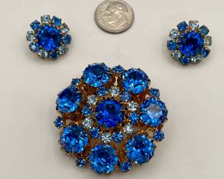 Sparkly vintage brooch and earrings marked Made In Austria. Gold-tone metal with different shades of blue rhinestones in flower pattern