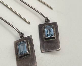 Closeup of sterling silver earrings, rectangle frames with faceted blue stone