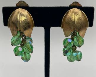 Closeup of vintage Aurora Borealis green crystal dangle earrings and matching brooch, gold tone metal