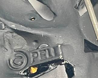 Closeup of makers mark on PELL leaf brooch, graceful curved black enameled frame with deep pink faceted rhinestones