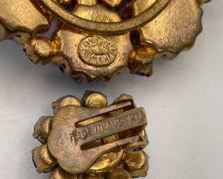 Closeup of sparkly vintage brooch and earrings marked Made In Austria. Gold-tone metal with different shades of blue rhinestones in flower pattern