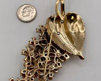 Reverse of vintage Crown Trifari brooch, heart-shaped gold tone metal leaf with stem of blossoms in a range of green faceted glass stones