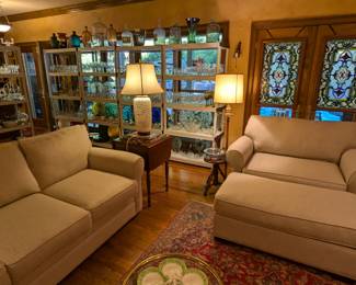 Great room, with couch and loveseat, by Cindy Crawford Home, vintage hand-woven Persian Lilihan Sarouk rug, vintage 3-legged piano stool, one of a pair of Biggs drop-leaf, 2-drawer, 1930's mahogany side tables, one of a pair of Asian porcelain lamps and a pair of stained glass panels.