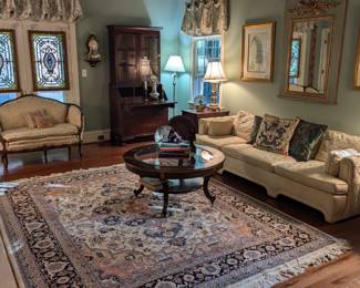 Master bedroom, turned den, with hand-woven Persian design Heriz wool rug measuring 8'4" x 10'6", tightly woven in Romania, round inlaid wood/beveled glass coffee table, long/low/lovely Asian-inspired couch, w/dragon embroidered pillows, pair of large, well framed vintage botanical prints, vintage French inspired trumeau wall mirror, pair of pencil inlay/leather topped single drawer 1930's mahogany side table, with bottom shelf, by Biggs, Furn. Co., Richmond, VA, 1930's mahogany secretary, by Biggs, Pair vintage porcelain table lamps on marble bases, vintage French loveseat,  upholstered armchair and matched pair of stained glass panels.