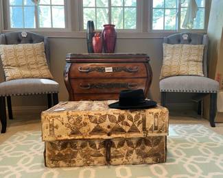Rawhide trunk, Huntington Home area rug, Dusky Upholstered Side Chair (A), Dusky Upholstered Side Chair (B), Stone top dresser, Decorative throw pillows
