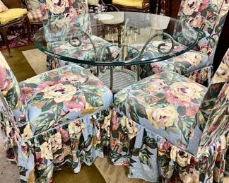 Lot #28: Iron and wicker glass topped table with four floral upholstered Parsons chairs on casters