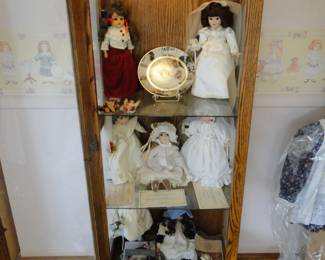 More dolls in a lighted curio cabinet