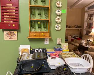 Calendars, glassware, trivets, Pyrex, bakeware, plate rack with various sets of plates