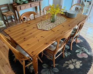 Pine farmhouse-style dining table with four chairs (the chairs at each end of the table belong to another set).