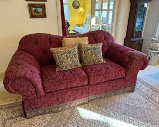 Pair of cranberry patterned couches with curved backs.