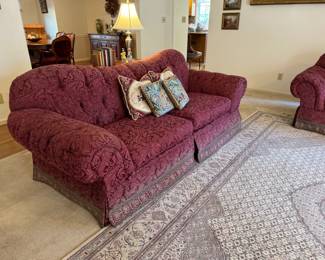 Pair of cranberry patterned couches with curved backs.