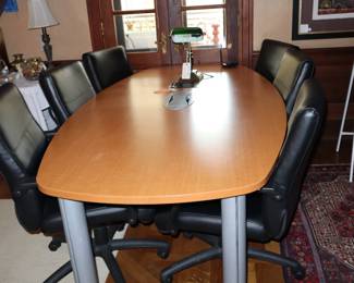 A new, modern conference table outfitted for equipment to be used on top. Six nice contemporary black leather pedestal, swivel chairs. All sold independently, located in Library. 