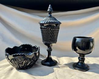 Various black glass pieces from Indiana Glass Company: black monarch daisy bowl (left), black diamond tiara lidded jar (center) and black amethyst goblet (right).