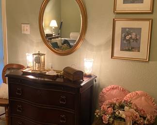 Three drawer chest of drawers
Gold oval mirror
ANTIQUE anniversary clock
Brass and glass table side lamps
Brass embossed box
Pink pillows and pink floral artwork