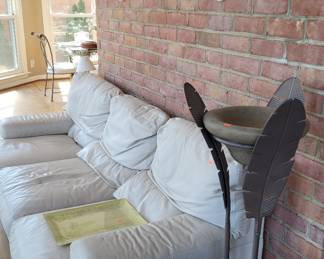 Beautiful creme colored leather sofa with fern stand and decorative wall decor masks