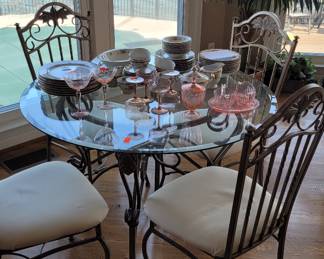 Very nice Round glass breakfast table with 4 matching chairs accented with decorative iron pedestal, chair legs and chair backs