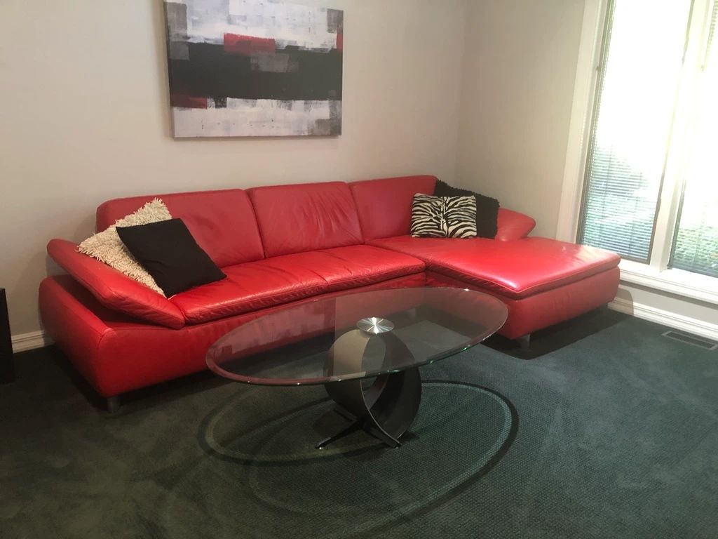 RED LEATHER SECTIONLAL ANDD OVAL COCKTAIL TABLE