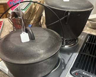 A pair of terrific Cast iron Dutch Ovens! The front one is medium size, the back one is large! 