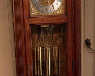 Antique Grandfather Clock with Ornate Dial - A beautifully crafted antique grandfather clock featuring an intricately designed clock face with golden accents. The clock is housed in a richly finished wooden case with elegant detailing and a glass door showcasing the pendulum and weights. The arched top adds a classic touch, and the clock's mechanism appears to be in good working order. This piece is a fine example of traditional clockmaking, likely from the early to mid-20th century. - $800