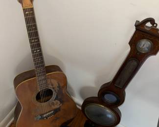 scruffy Yamaha FG-300 guitar cozying up with the family barometer