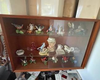 Covered curio shelf with ceramic collectibles.