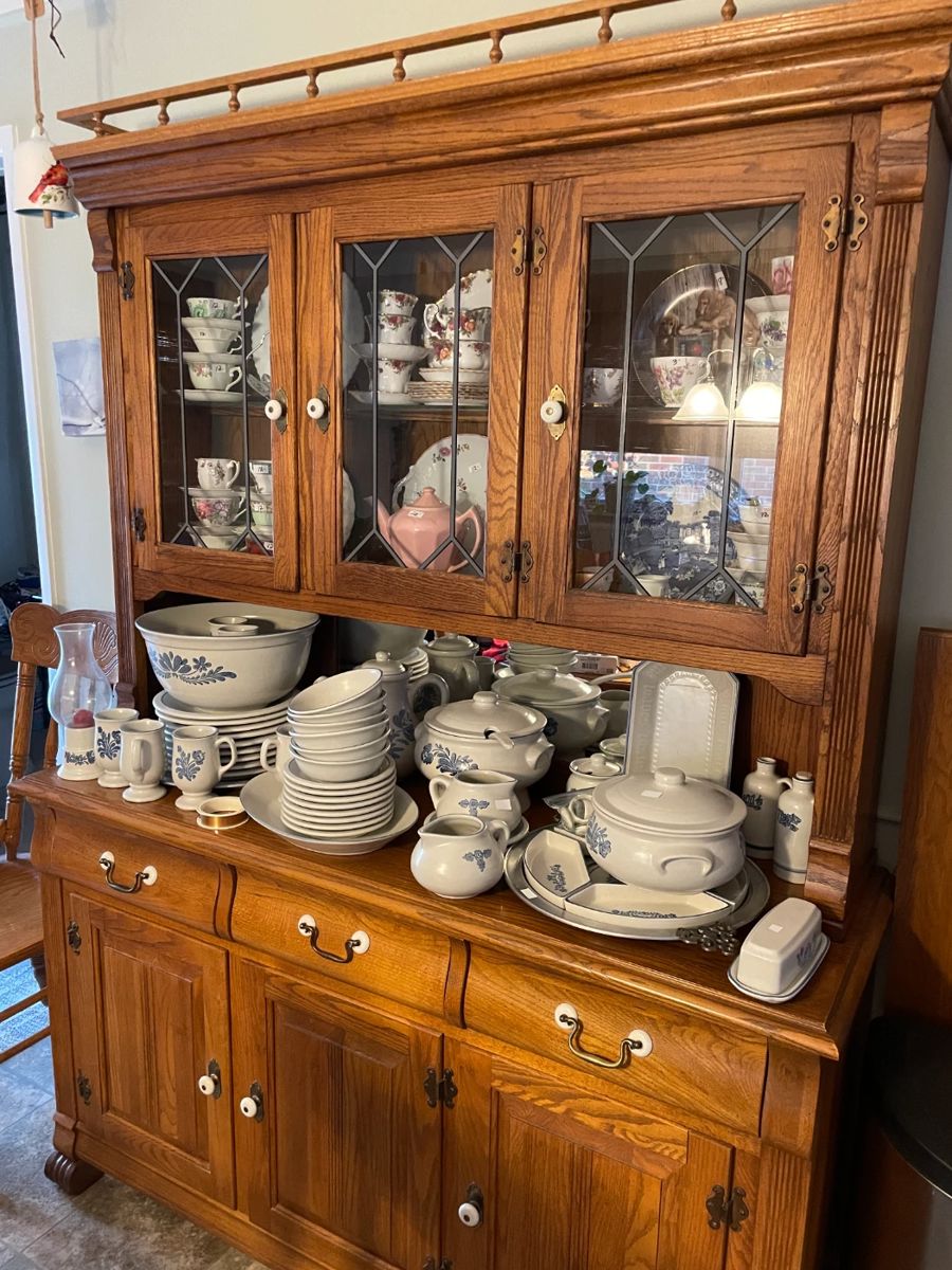 . . . oak lead-glass china hutch filled with English cups and saucers and Yorktown Pfaltzgraff stoneware china