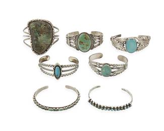 296
A group of Southwest silver and turquoise cuff bracelets
Mid/late 20th century
Three marked: Sterling; one marked: H Jim; one for Wheeler Manufacturing Co.
Comprising two narrow row-set cuffs, one by Harrison Jim (Navajo/Diné), and a three-wire cuff with large set slab turquoise, as well as a sterling silver two-wire cuff with elaborate feather and floral silver overlay designs, and three Fred Harvey-style cuffs, each with set turquoise and stampwork motifs, 7 pieces
Largest: 6 1/4" inner C x 2 1/4" H; smallest: 6" inner C x 5/16" H
166.4 grams gross
Estimate: $500 - $700